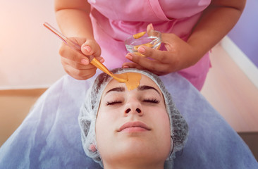 Facial cosmetic procedure in spa salon. The procedure for applying a mask to the face of a beautiful woman