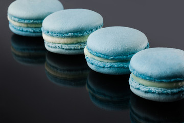 Fototapeta na wymiar French macarons. Stack of blue macaron with dorblu and wine isolated on dark mirror background. Colorful macaroons. Top view