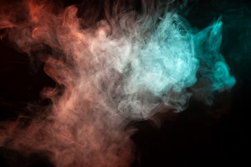 Multicolored smoke from a vape of green and red color of the strange mystical form on on a black isolated background. Bright clouds in the abstract form.