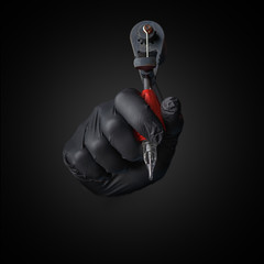 Tattooist hands in black gloves with tattoo machine on dark gray background.