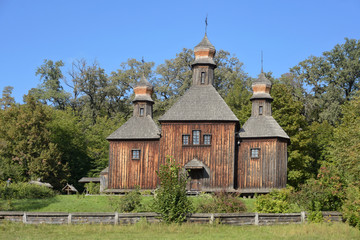 Obraz premium old wooden churchBeautiful old wooden church with wooden fence on green summer background and blue sky