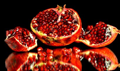 close up of a red cut pomegranate with seeds on a black background
