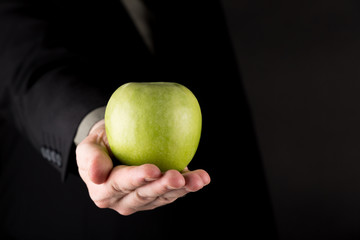 Business man in suit giving a Green Apple, isolated on gradient gray background, copy space