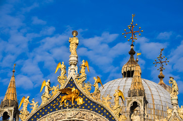 view of San Marco Cathedral in Venice, Italy with saints, crosses and blue sky