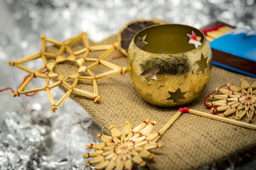 Golden Christmas decoration with straw stars, candlesticks and matches with shiny silver background