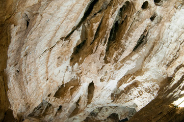 Dark cave view from inside with a lumen. Stalactites and stalagmites inside the stone grotto. Colorful stones in the cave. Lighting electricity beauty of the cave.