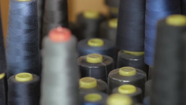 CLose up of coils with colored threads. Bobbins are stacked in rows, one on the other.