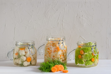 Fermented preserved vegetarian food concept. Cabbage, broccoli, caulie, sauerkraut sour glass jars on white background