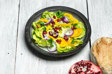 Healthy breakfast, fresh salad with the addition of purple onion and pomegranate seeds on white, wooden background