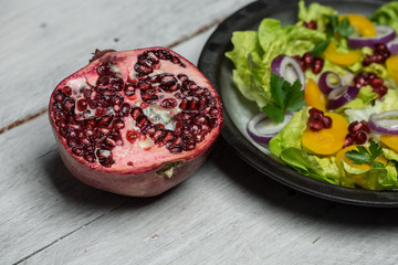 Healthy breakfast, fresh salad with the addition of purple onion and pomegranate seeds on white, wooden background