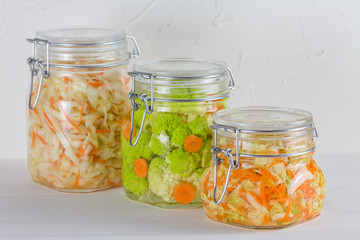 Fermented preserved vegetarian food concept. Cabbage, broccoli, caulie, sauerkraut sour glass jars on white background