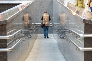 Entrance to the underground passage with shiny railing and double reflection of a man