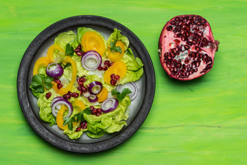 healthy diet, fresh salad with the addition of purple onion and pomegranate seeds on green background