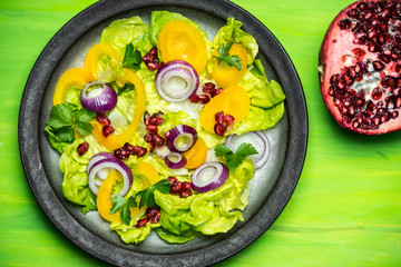 healthy diet, fresh salad with the addition of purple onion and pomegranate seeds on green background