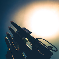 Four rockets of anti-aircraft missile system are directed upwards against a background of bright sun