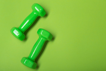 two green dumbbells on a green background, concept, copy space