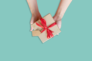 top view hand woman holding brown gift box for new year on green pastel color background with space.