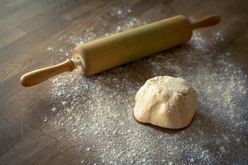 Pie dough and rolling pin on a wooden table covered with flour