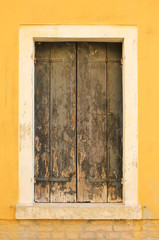 Obraz na płótnie Canvas Rustic brown wooden window shutters with stone wall yellow background. Burano, Venice
