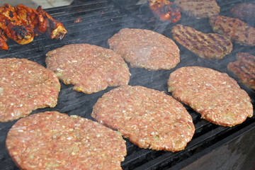 Grilling sausages, burgers, pork steak on barbecues gas grill for party. Hot dogs,sausages and hamburgers on a barbeque, bbq. Smokes meat food outdoors, fast food. Hamburgers. Pleskavitsa