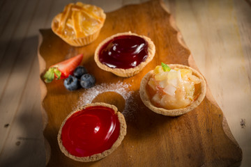 Strawberry and blueberry tart with various jam pies, fresh homemade bakery on wooden background, selective focus