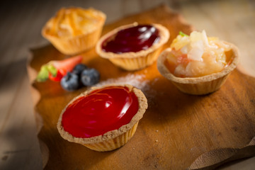 Strawberry and blueberry tart with various jam pies, fresh homemade bakery on wooden background, selective focus