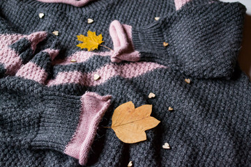 Fototapeta na wymiar Women's sweater decorated with autumn leaves. Sweater texture. Cold season.