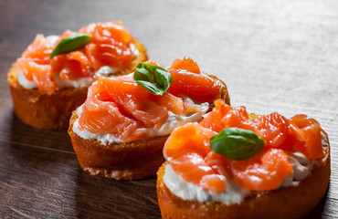 Canapes with smoked salmon and cream cheese on wooden table background