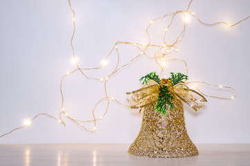 Christmas decoration in the form of a golden bell on a white background. Lights of garland on a white background.