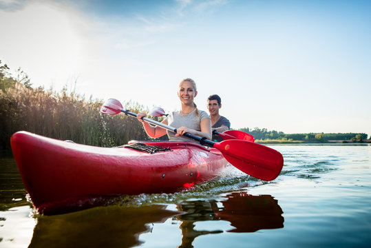 Happy Couple Rowing Kayak On Lake