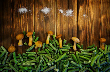 Frozen fungus mushrooms, green beans and salt on a wooden background