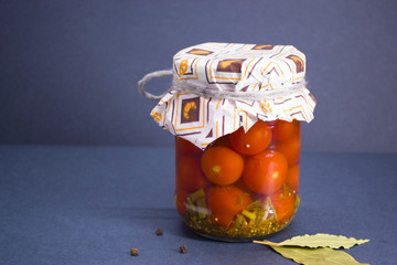 Salted tomatoes in a glass jar prepared for the winter and Bay leaf and black pepper.