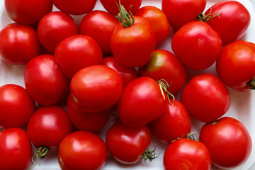 red tomatoes on a white plastic tray. Tray with fresh raw organic tomatoes on white background. vegetables just collected from the garden.