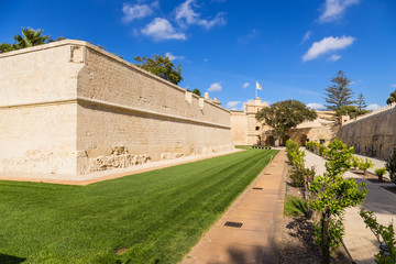 Naklejka premium Mdina, Malta. Former fortress moat turned into a park, walls, gate, bridge