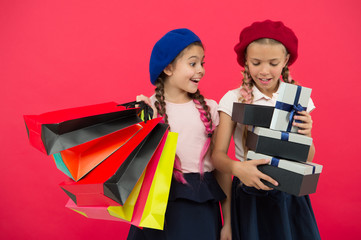 Shopping become fun with best friends. Children satisfied by shopping red background. Obsessed with shopping and clothing malls. Shopaholic concept. Kids cute schoolgirls hold bunch shopping bags