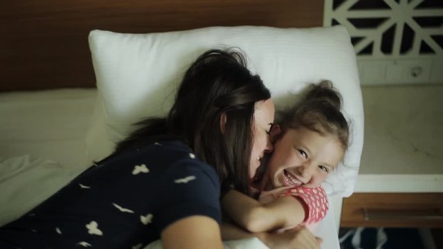 Woman waking young girl in bed smiling, Mother coming to the sleeping child