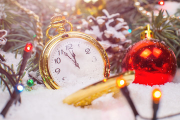 Fototapeta na wymiar A vintage clock in the snow against the background of a Christmas tree and a garland