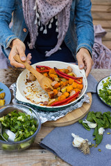 Woman take, mix with spatula baked, roasted, grilled vegetables in white cast iron skillet, pan with spices and herbs. Red bell pepper, pumpkin, potato, zucchini, Vegan, vegetarian healthy food