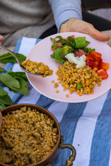 Woman hand put, add lentil to buddha bowl plate with red pepper bell salad, cooked vegetables (broccoli, brussels sprouts, cauliflower), spinach, grapefruit, lentil. Vegan vegetarian healthy food