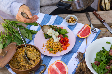 Hand put, add vegetables to buddha bowl plate with red pepper bell salad, cooked vegetables (broccoli, brussels sprouts, cauliflower), spinach, grapefruit, Indian lentil. Vegan vegetarian healthy food