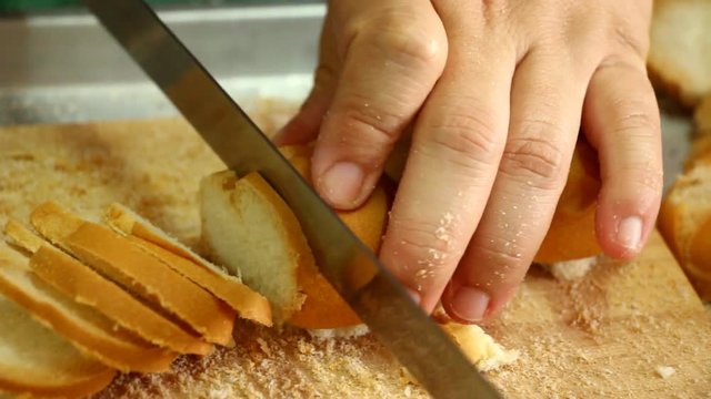 Chef  cutting bread by bread knife 
