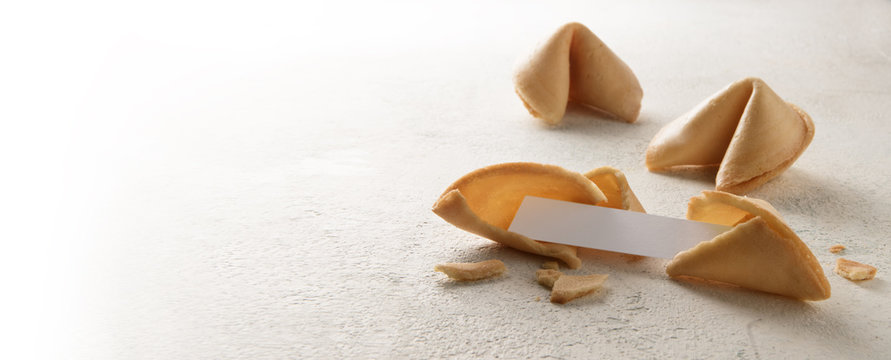 chinese fortune cookies with a blank paper slip for the prediction, panoramic format, bright background fades to white, copy space