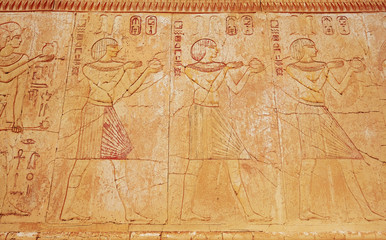 Fototapeta na wymiar Ancient egypt scene. Hieroglyphic carvings on the exterior walls of an ancient egyptian temple. Grunge ancient Egypt background.
