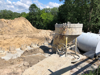 yellow concrete pouring device on the background of concrete piles in the ground and soil. iron...