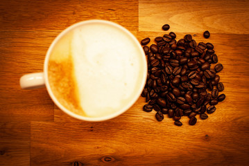 A cup of coffee with oat milk and some coffee beans