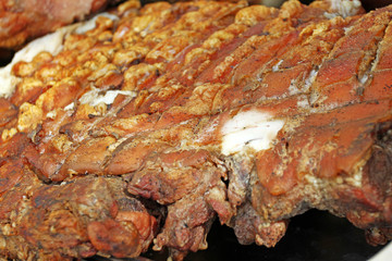 Big piece of roasted pig meat with cuuting knifes. Swine baked on a rotating grill -cheverme. fast food and fat concept. pieces of meat prepare for eating. Christmas festival market.
