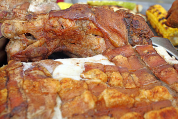 Big piece of roasted pig meat with cuuting knifes. Swine baked on a rotating grill -cheverme. fast food and fat concept. pieces of meat prepare for eating. Christmas festival market.