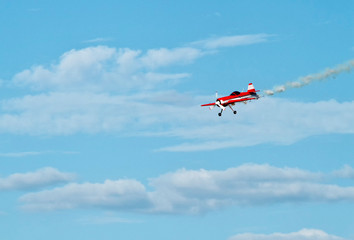 red retro airplane in the blue sky during airshow, airplane trail