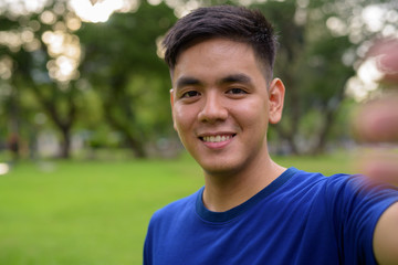 Young handsome Asian man taking selfie with mobile phone