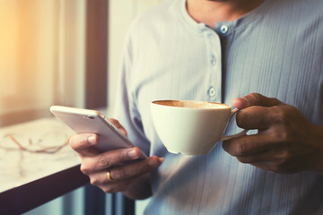 hand holding coffee cup and using smart phone